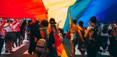 A group of people walking under a Pride flag