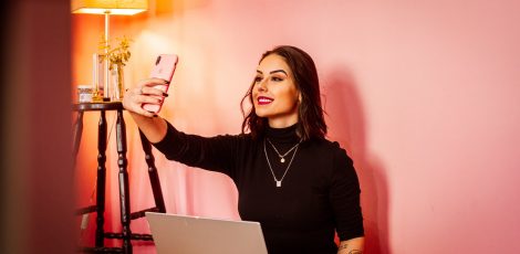 Influencer taking a selfie behind a laptop
