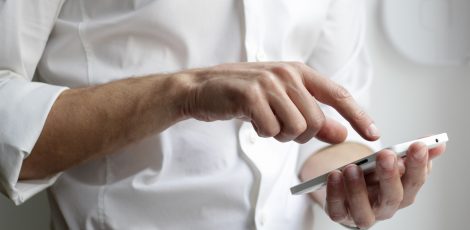 Person in a white shirt holding a smartphone